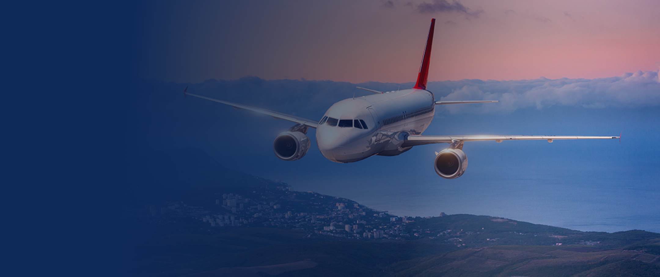 Airplane flying over city at sunset